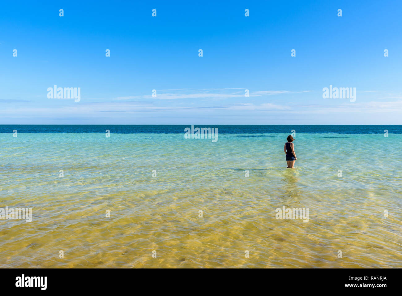 Young attractive woman in shorts standing on the sea shore of a tropical beach. Beautiful turquoise ocean water. Bahia Honda State Park, Florida Keys Stock Photo