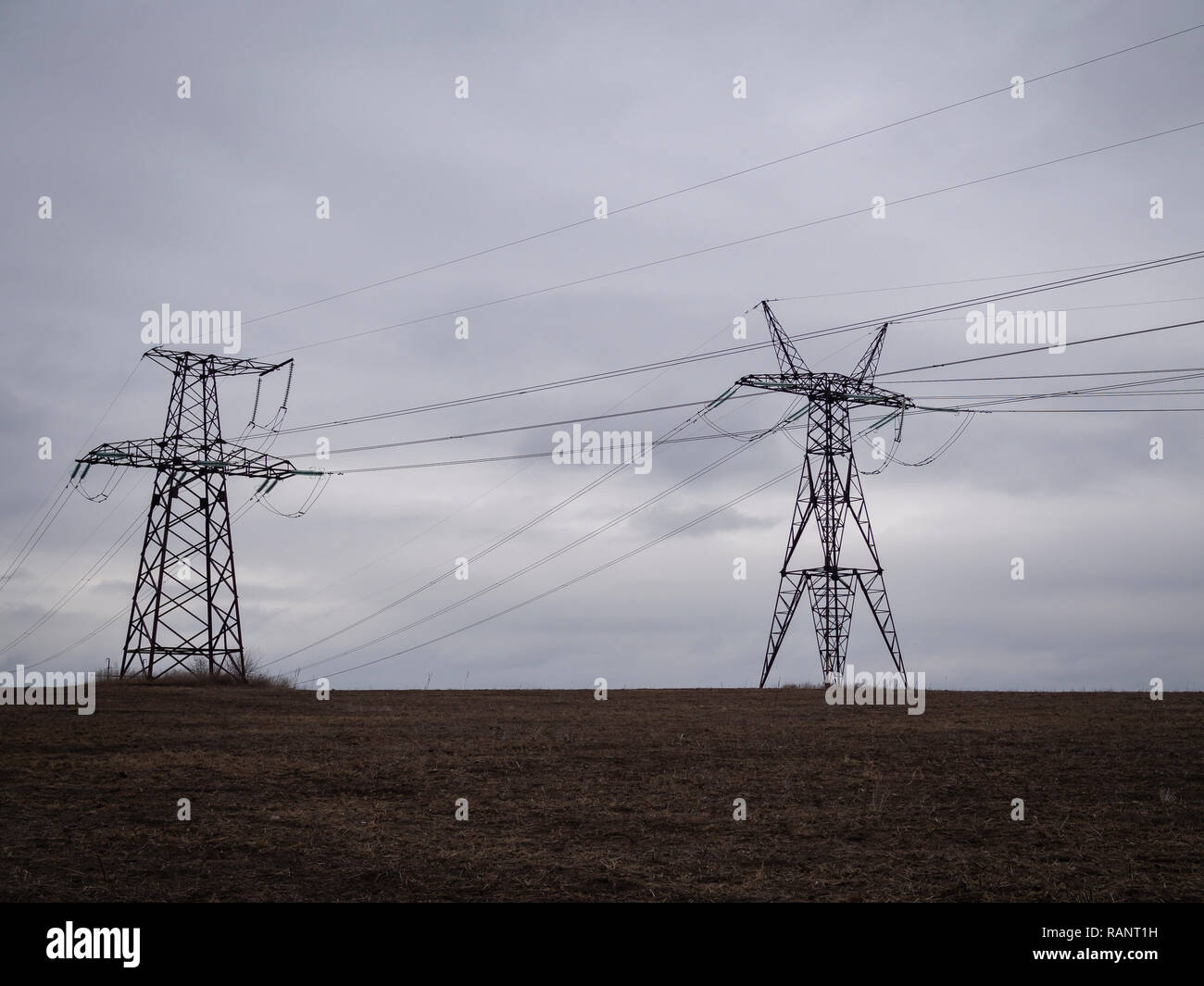 Overhead power line towers in cloudy day Stock Photo