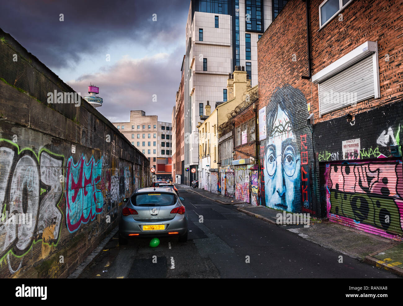 A moody scene of the back alley of Cropper Street, Liverpool with a John Lennon mural and other graffiti. Stock Photo