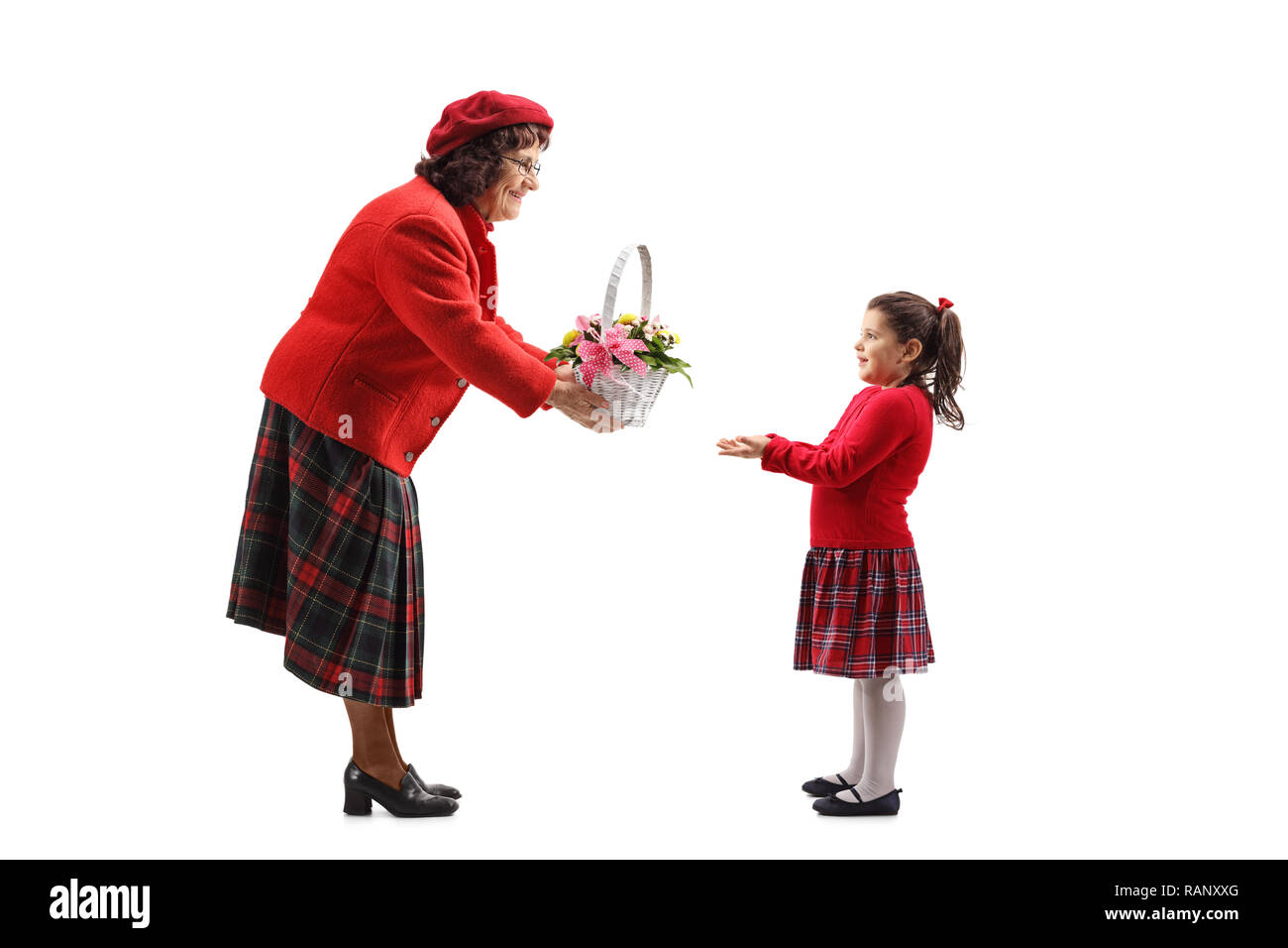 Full length shot of a grandmother giving a basket of flowers to her granddaughter isolated on white background Stock Photo