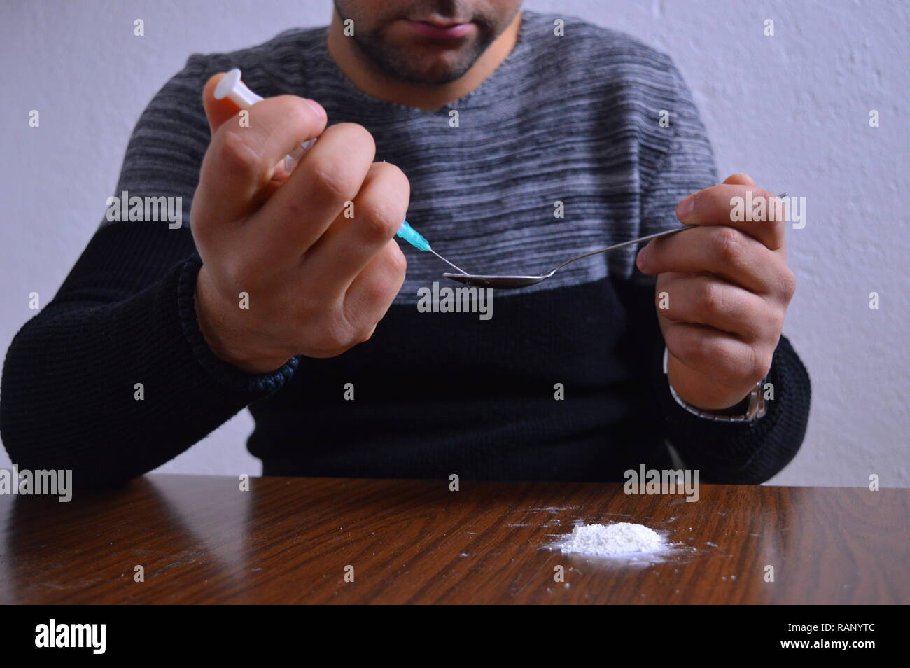 A person injecting a drug in his arm with a syringe Stock Photo