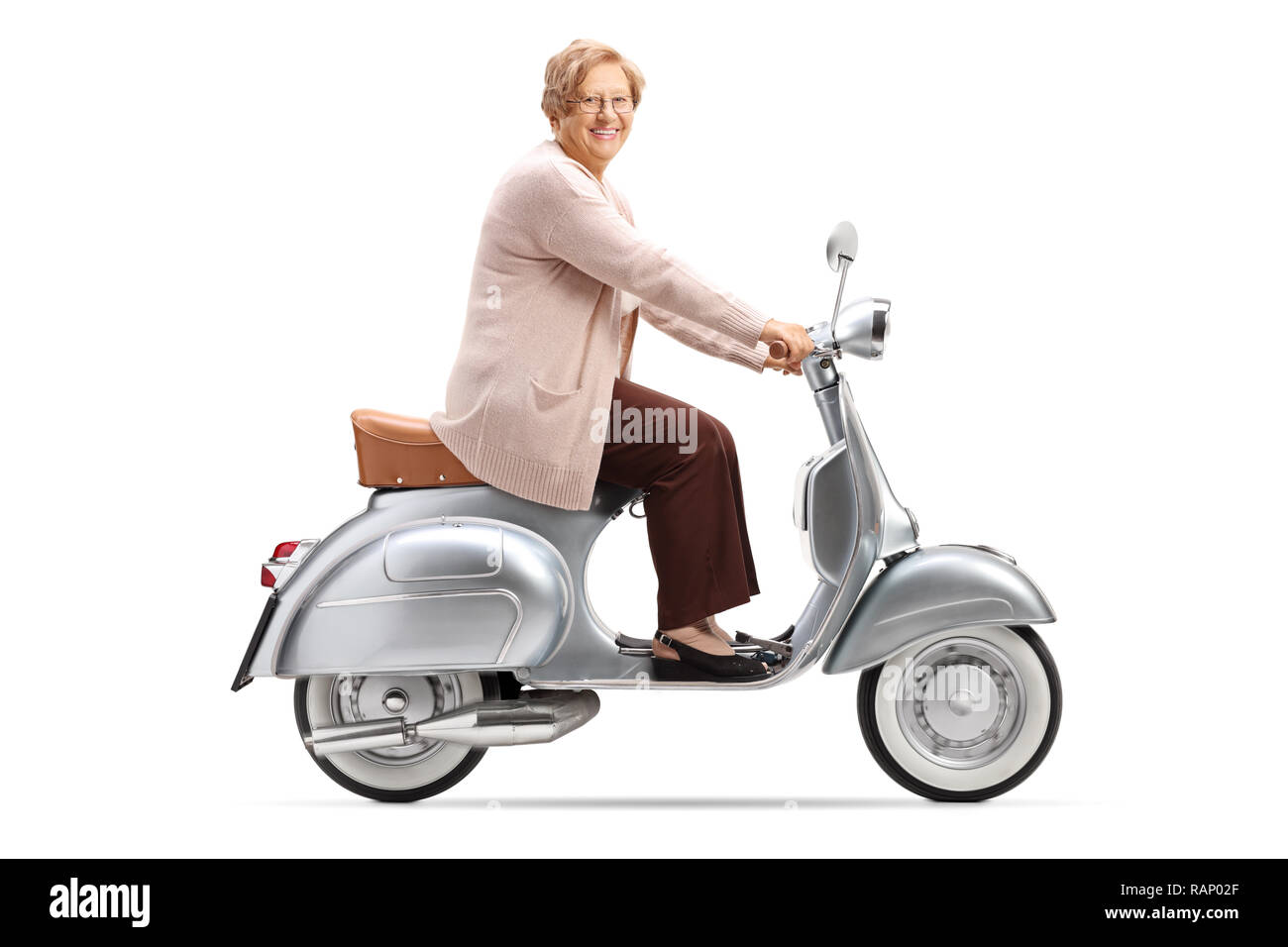 Full length shot of a senior woman riding a vintage scooter and smiling at the camera isolated on white background Stock Photo