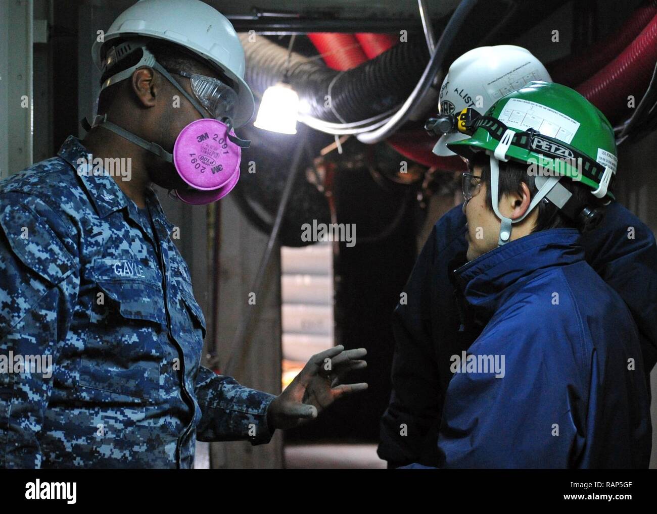 YOKOSUKA, Japan (Feb. 22, 2017) - Hospital Corpsman 3rd Class Patrick Gayle from Jacksonville, Fla., attached to the U.S. 7th Fleet flagship USS Blue Ridge (LCC 19), speaks with personnel from Ship's Repair Facility Yokosuka. Blue Ridge is in an extensive maintenance period in order to modernize the ship to continue to serve as a robust communications platform in the U.S. 7th Fleet area of operations. Stock Photo