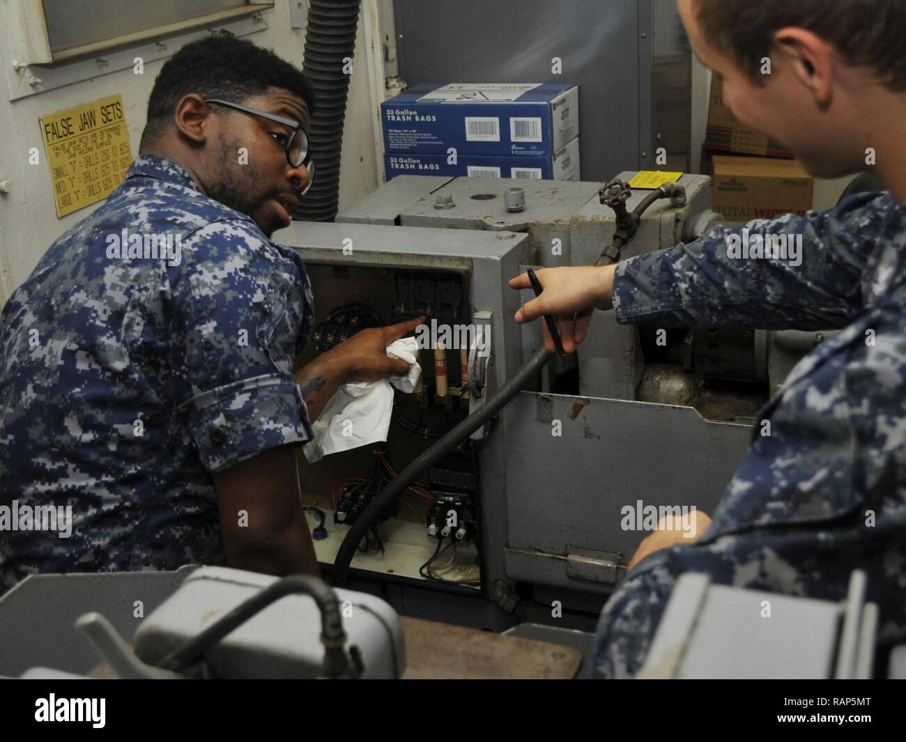 POLARIS POINT, Guam (Feb. 22, 2017) Electrician's Mate Fireman Ketab Hairston and Electrician's Mate 2nd Class Erik Wenthe, both Sailors assigned to the submarine tender USS Emory S. Land (AS 39), conduct maintenance on a grinder drill in the ship's machine shop. Emory S. Land, homeported in Guam, provides maintenance, hotel services and logistical support to submarines and surface ships in the U.S. 5th and 7th Fleet areas of operations. Stock Photo