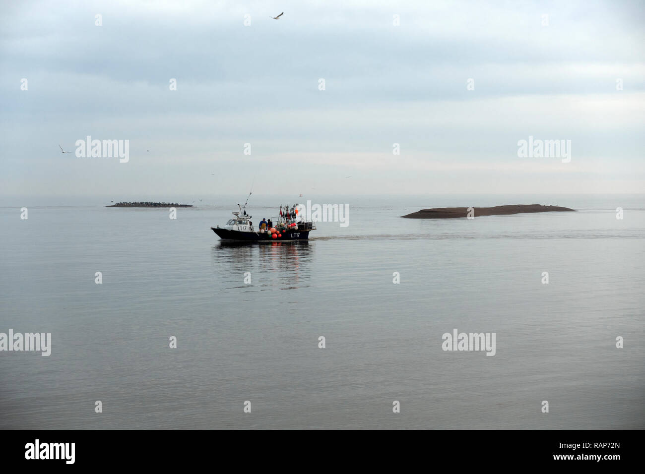 Fishing boat entering the river Ore from the North Sea, Shingle Street, Suffolk, UK. Stock Photo