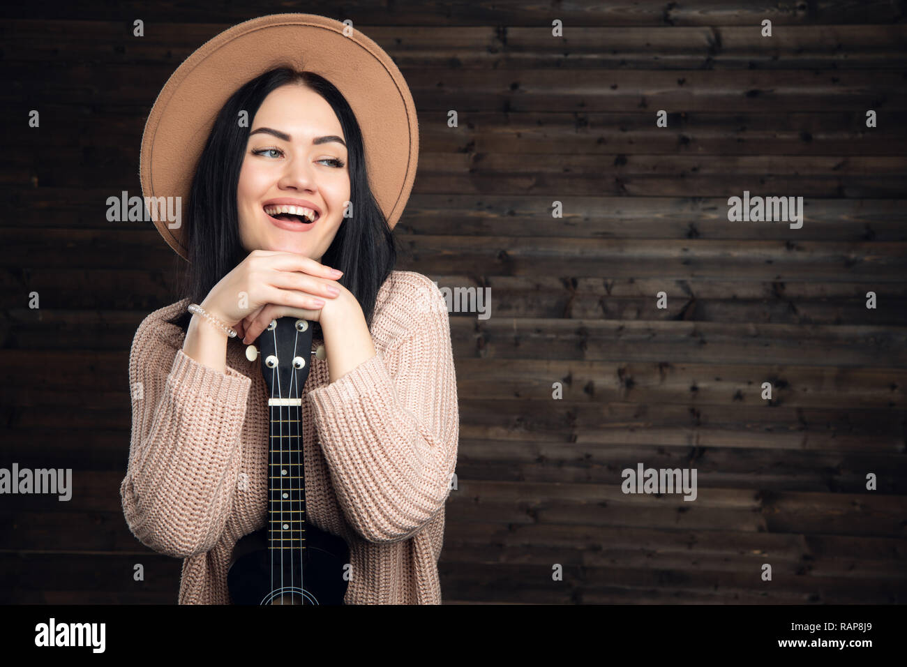 Woman sit with ukulele at home and smiling Stock Photo