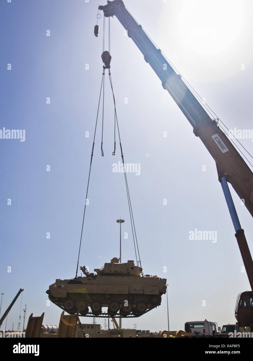 A M2/M3 Bradley Fighting Vehicle is transported via crane onto a flat bed truck to be put on the USNS Mendonca at Shuaiba Port, Kuwait, on Feb. 28, 2017. The Mendonca is used to import and export U.S. Military vehicles in support of operations in the USCENTCOM AOR. Stock Photo