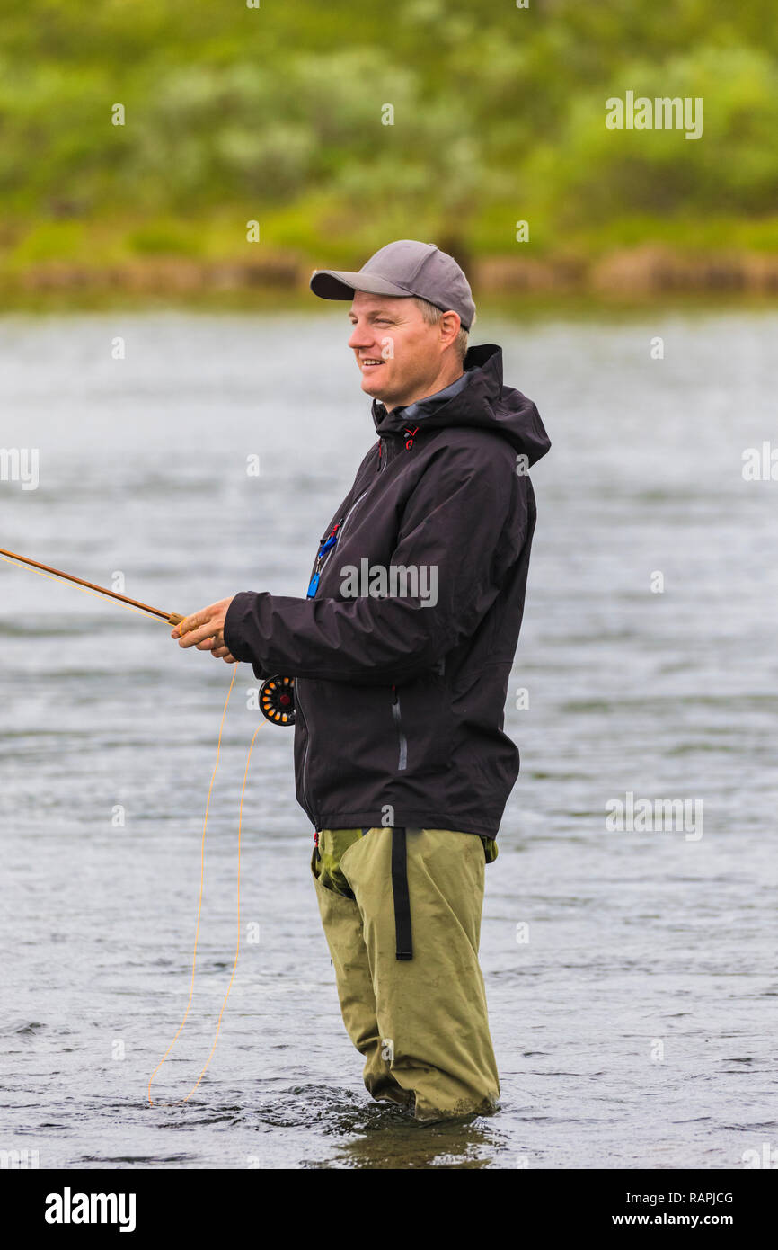 White man fishing, standing in the water, looking happy and