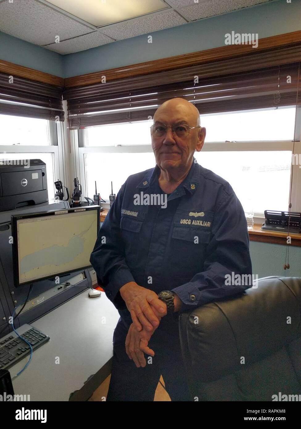 Coast Guard Auxiliary member John Steinbarge mans the communication room at Coast Guard Station Oswego, New York, Feb. 15, 2017. Coast Guard Auxiliary members are unpaid volunteers who assist at Coast Guard units throughout the country filling various roles. Stock Photo