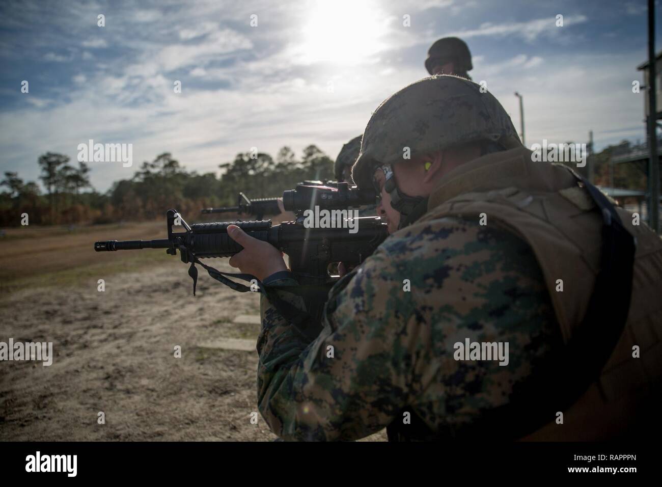 A Marine looks downrange with a rifle combat optic to accurately fire at targets set at unknown distances, at Camp Lejeune, N.C., Feb. 23, 2017. The Marines spent the day at the range to achieve their annual rifle qualifications and to refresh their rifle skills for day and night-time shooting. The Marine is with 2nd Maintenance Battalion, Combat Logistics Regiment 25, 2nd Marine Logistics Group. Stock Photo