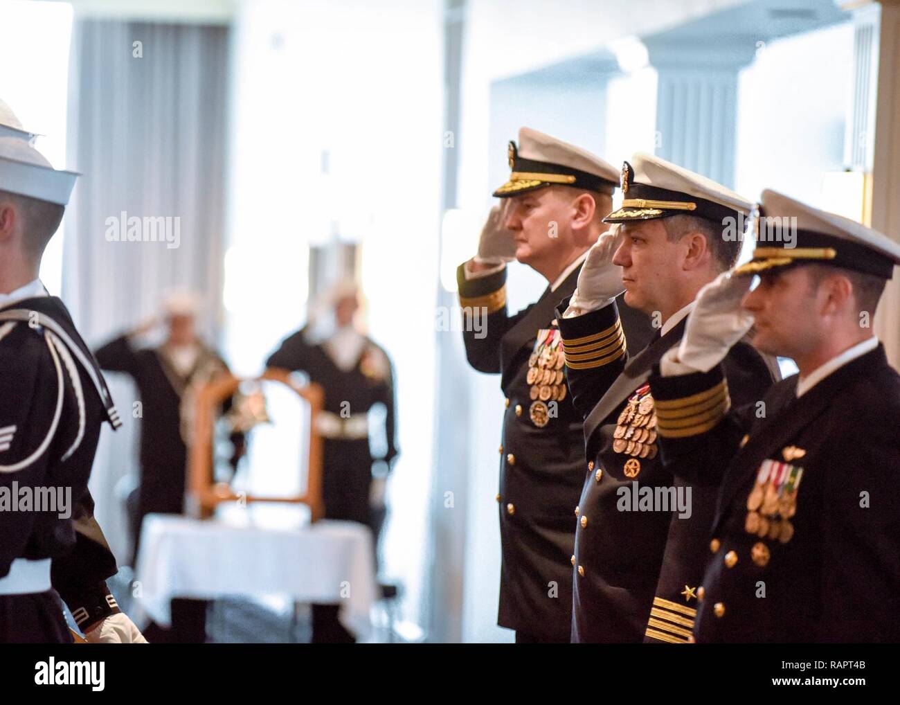 Navy Capt. Clyde F. Mays, Jr. (middle) salutes the American Flag during his change of command ceremony for Joint Base Anacostia-Bolling in Washington, D.C., Feb. 24, 2017 at the Bolling Club. Mays, a native of Hickory, North Carolina, served as JBAB commander from March 2014 until February 2017. He was the third base commander since its inception in 2010. He was relieved by Navy Capt. Jose L. Rodriguez (right) of Queens, New York. The two-part ceremony also included a retirement ceremony for Mays, honoring his 34 years of active-duty service. Stock Photo