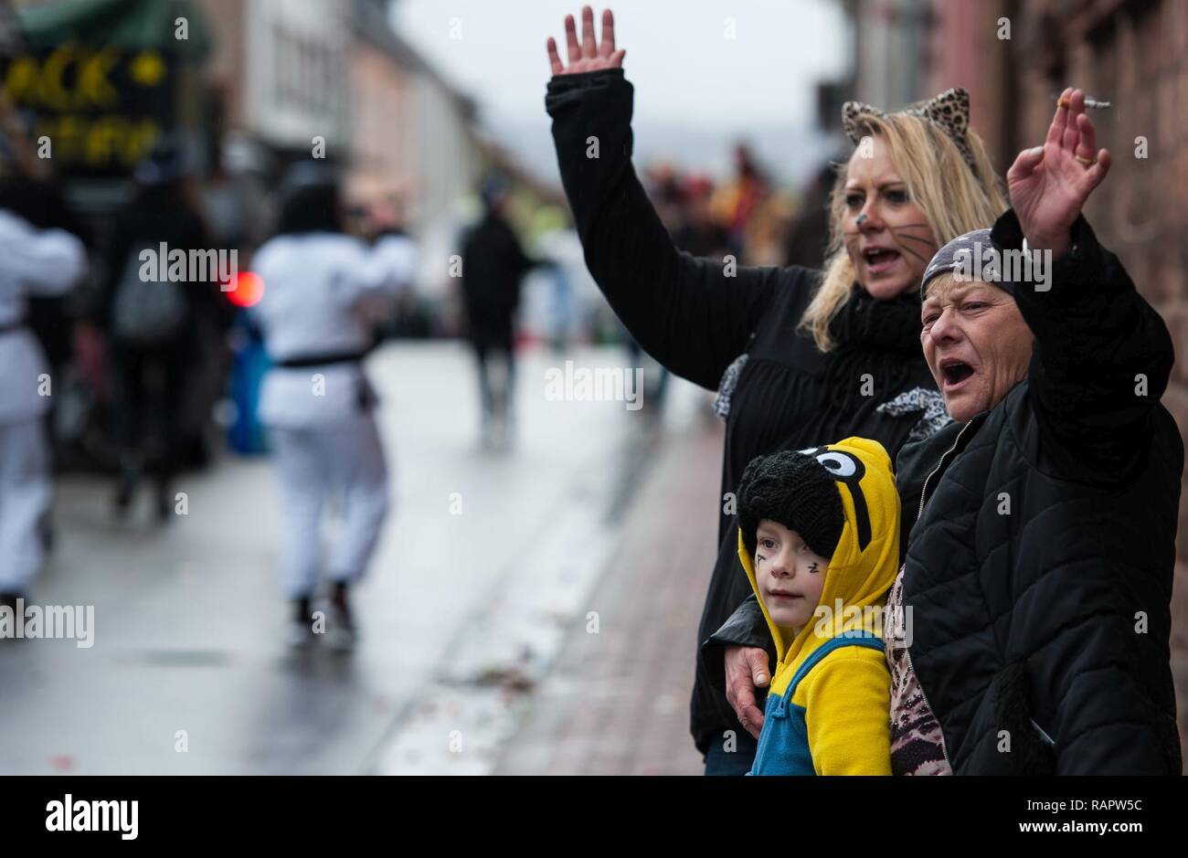 People wave at people in a parade during fasching, a festival held across Europe, in the city of Ramstein, Germany, Feb. 28, 2017. In the Middle Ages, Karneval gave people a break from the tightly structured class system, as they were able to hide their social background behind imaginative costumes and masks. Stock Photo