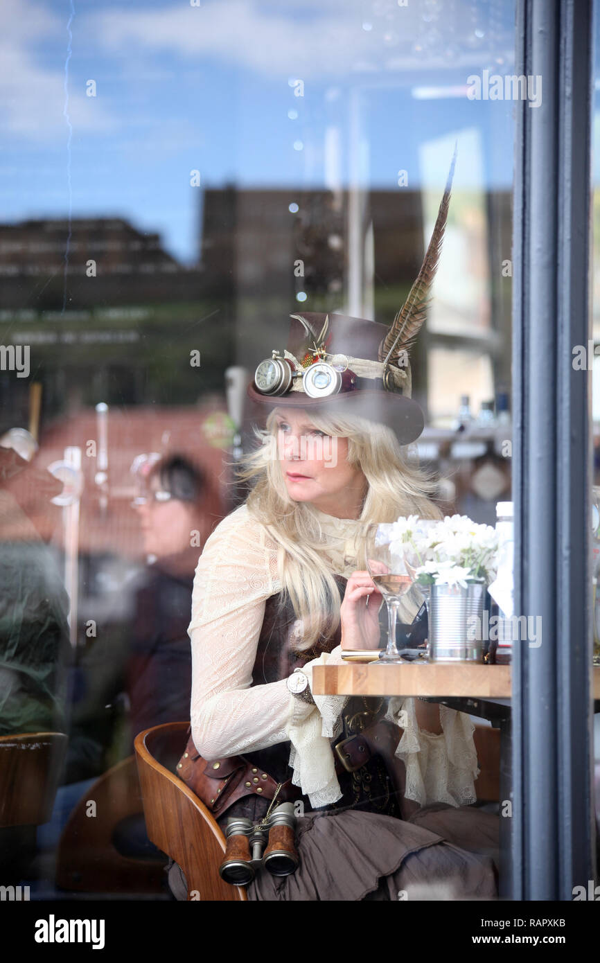 Steampunk lady enjoying refreshments in te window of a cafe at the famous Whitby Goth Weekend Festival. Stock Photo