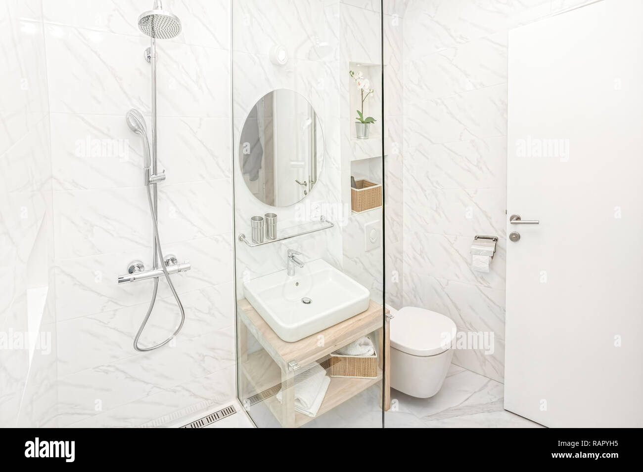 Bright new bathroom interior with glass walk in shower with marble tile surround Stock Photo