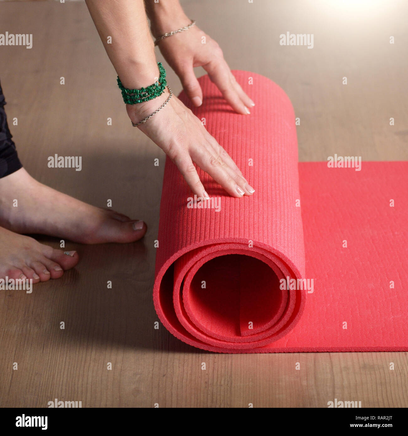 Female hands unrolling yoga mat before workout exercise. Healthy lifestyle concept Stock Photo