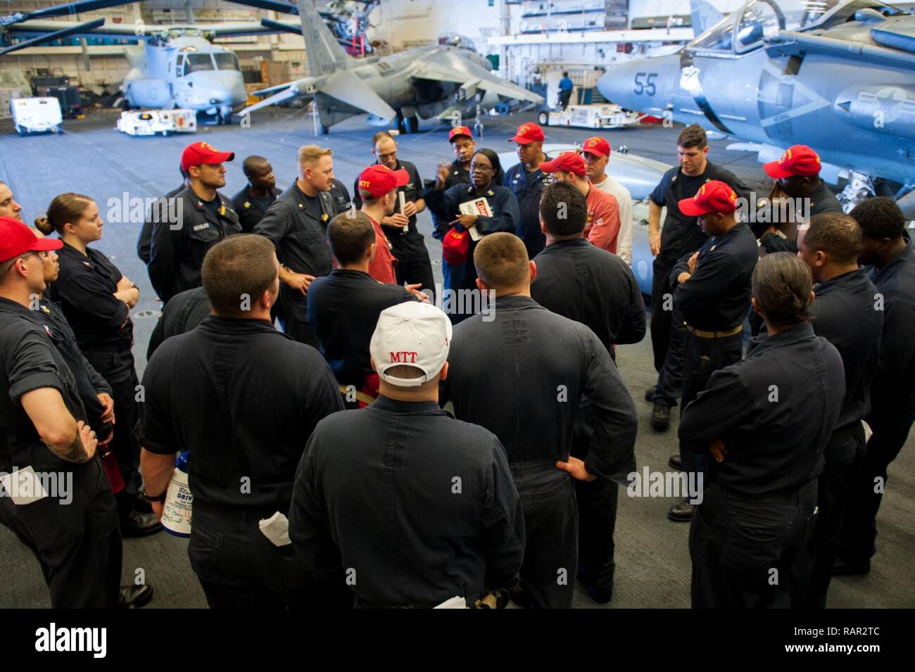 SOUTH CHINA SEA (Aug. 5, 2017) Damage control training team members aboard the amphibious assault ship USS America (LHA 6) gather in the ship’s hangar bay for a debrief following a general quarters drill. America, part of the America Amphibious Ready Group, with embarked 15th Marine Expeditionary Unit, is operating in the Indo-Asia Pacific region to strengthen partnerships and serve as a ready-response force for any type of contingency. Stock Photo