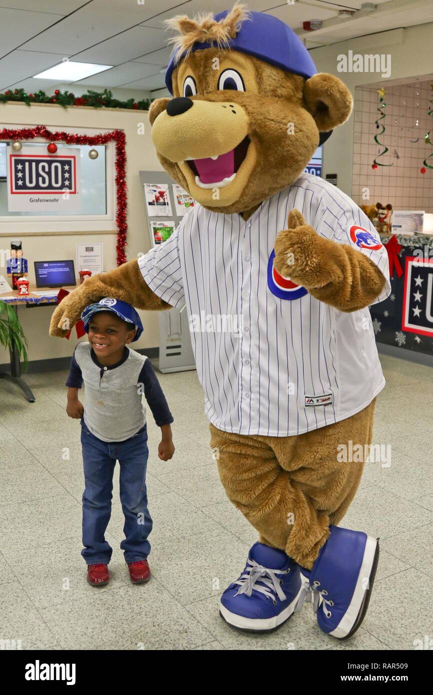 A U.S. Army Soldier's son poses with Clark, the Chicago Cubs mascot, at the  USO at USAG Bavaria in Grafenwoehr, Germany, Dec. 11, 2018. The USO  sponsored a Chicago Cubs mascot tour