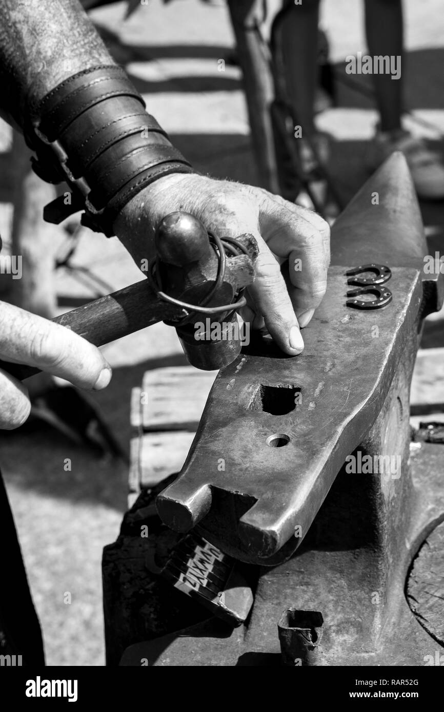 Blacksmith working on an old anvil next to his tools outside with daylight Stock Photo