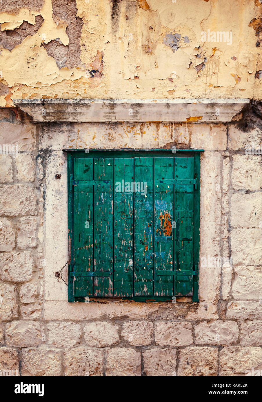 Green wooden  shutter in window on stone wall. Stock Photo