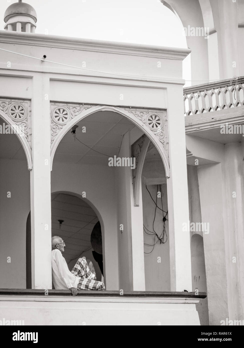Older man siting in front of mosque alone, Banda island, Indonesia, Asia Stock Photo