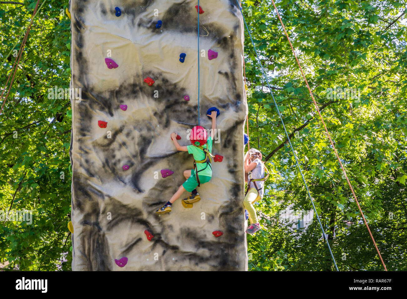 Children learning to rock climb on outdoor artificial climbing wall