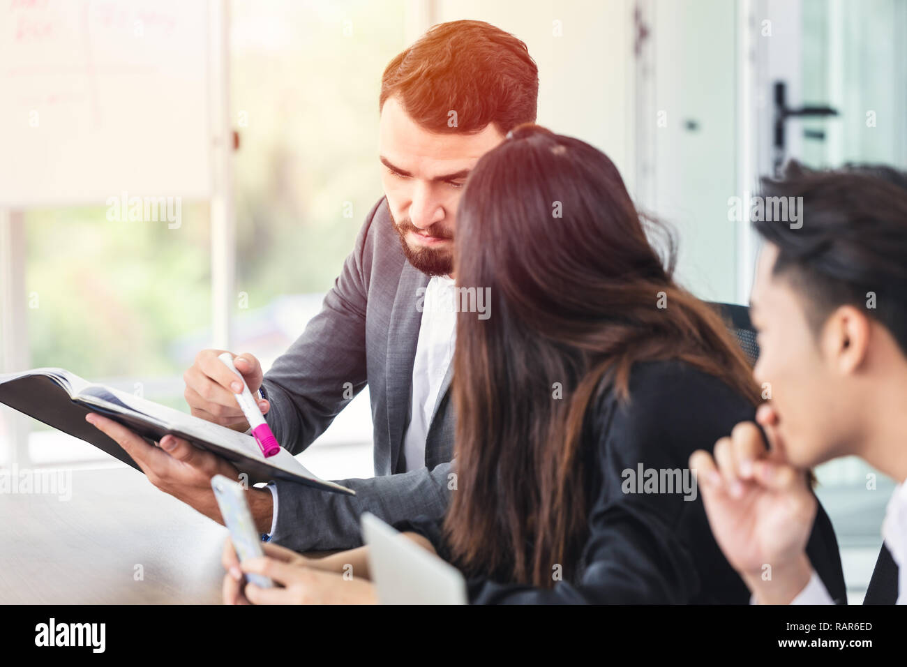 caucasian manager looking at report and discussion with business team at meeting room. Stock Photo