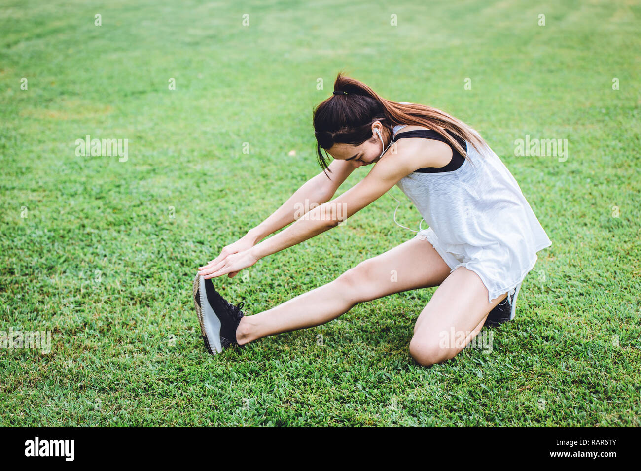 healthy slim girl leg stretching warm up before running or jogging