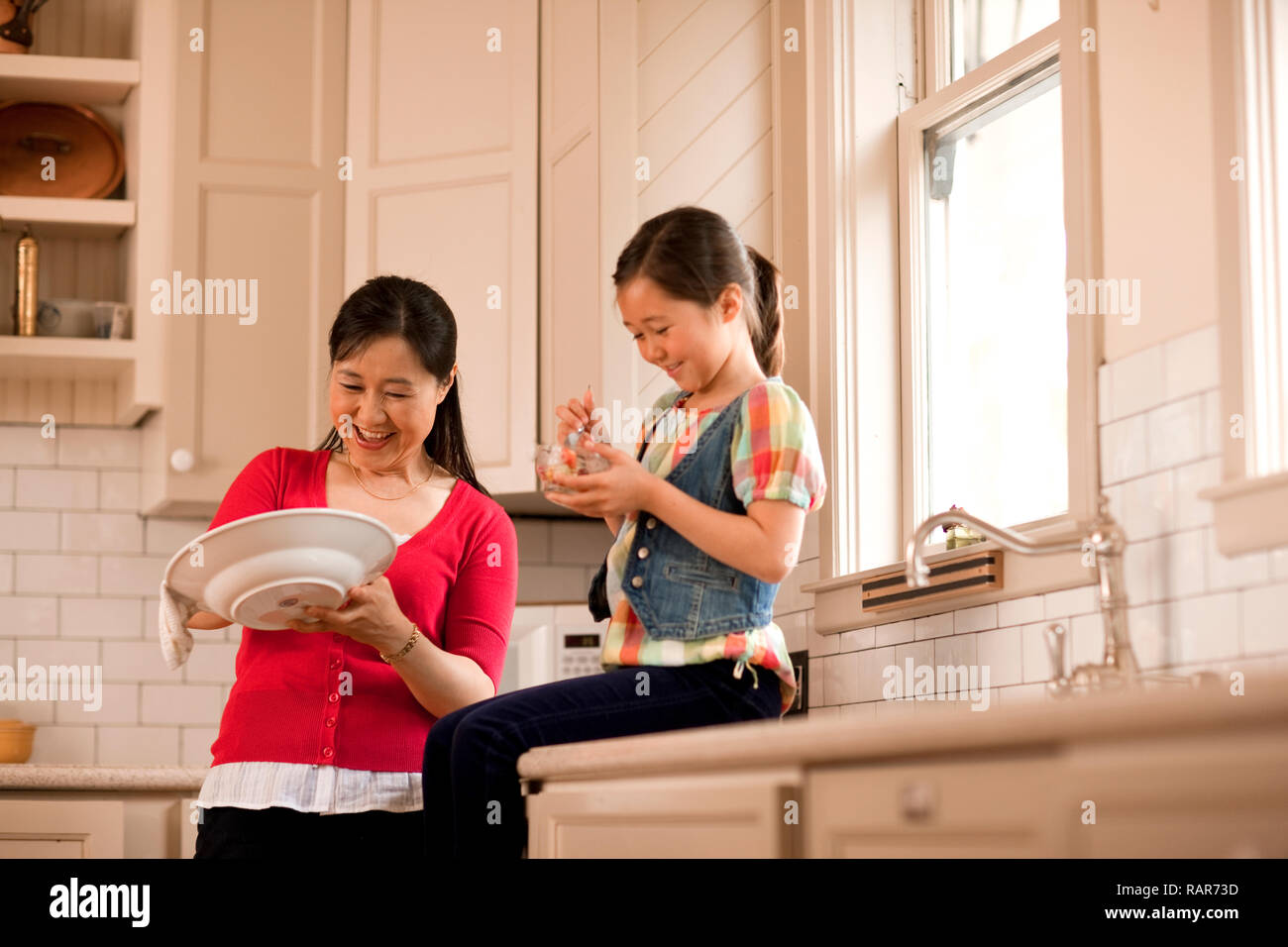 Woman doing the dishes with her granddaughter. Stock Photo