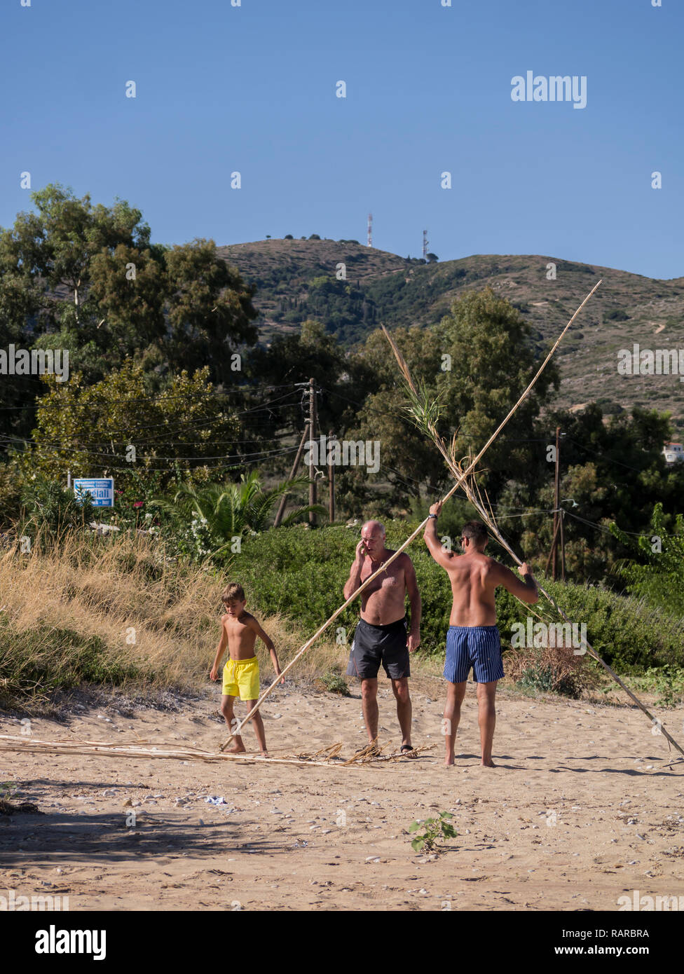 Male family group building a wigwam on the beach Stock Photo
