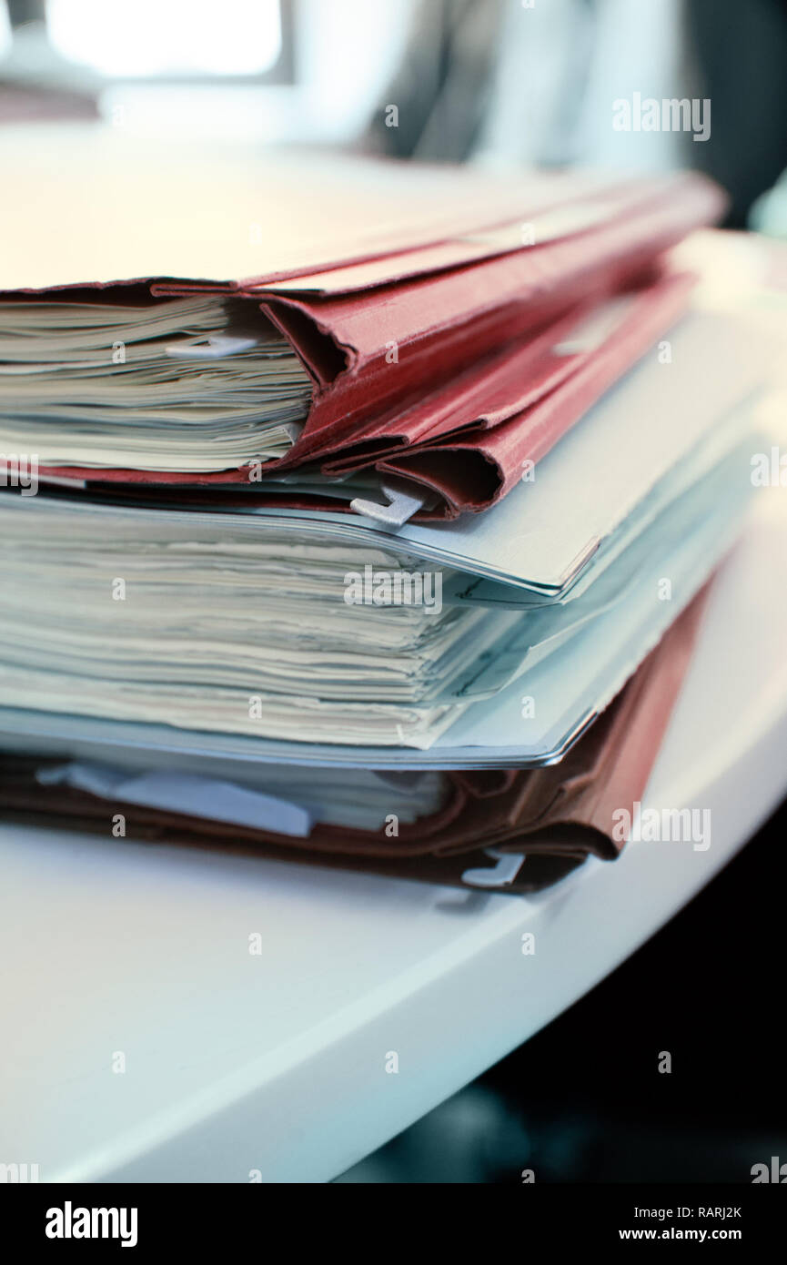 A pile of paper documents on a white desk. Stock Photo