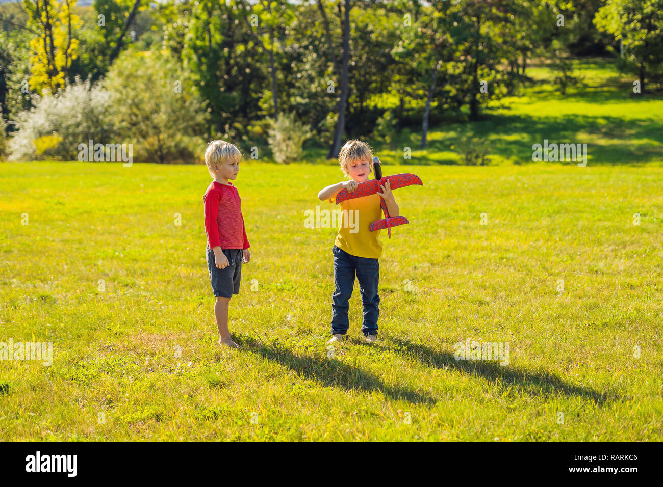 Two happy boys playing with toy plane in the park Stock Photo - Alamy