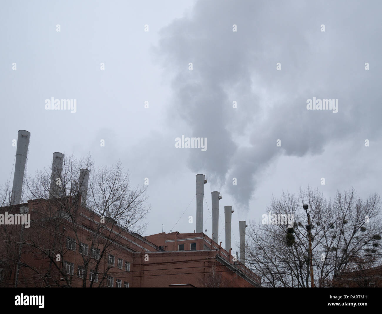 wide photo of factory plant pipe chimneys with smoke in air. smog is all around city, global pollution concept which cause medical problems like cance Stock Photo