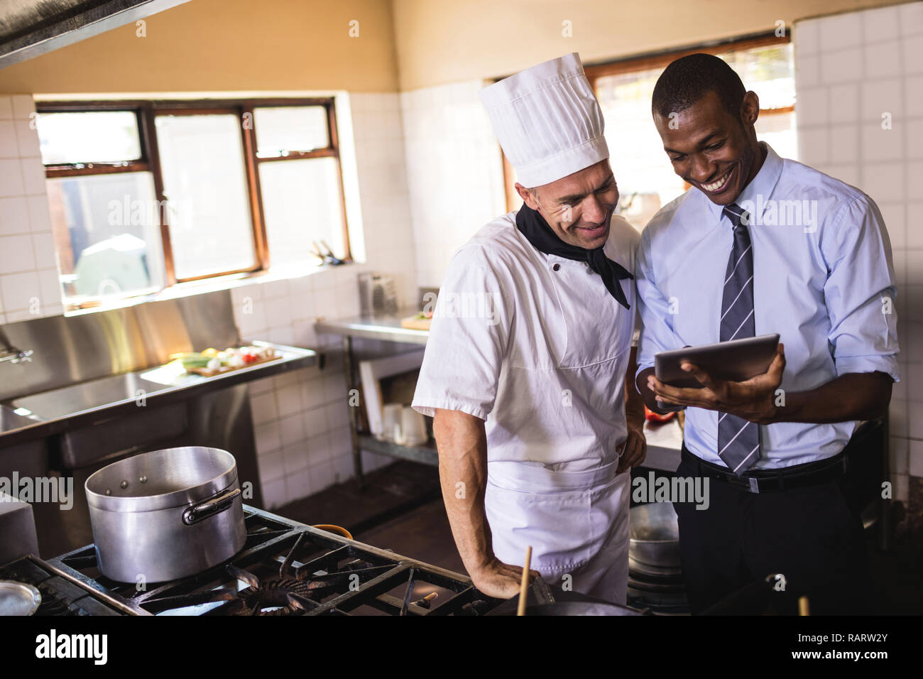 Male manager and chef using digital tablet in kitchen Stock Photo