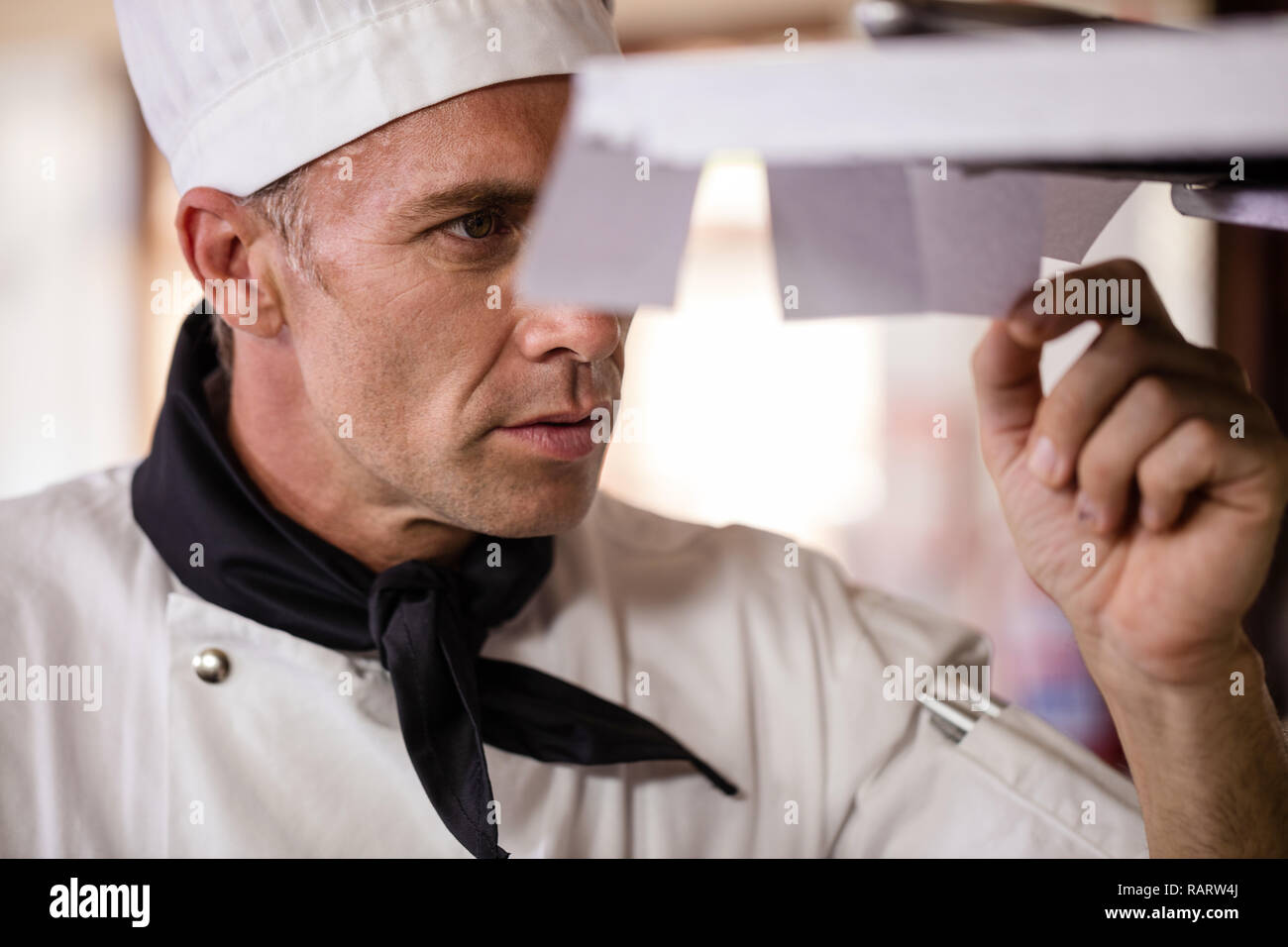 Male chef looking at order list in kitchen Stock Photo Alamy