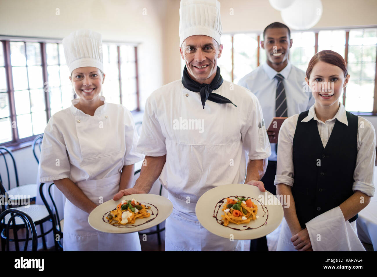 Male chefs holding plates with prepared food in hotel Stock Photo