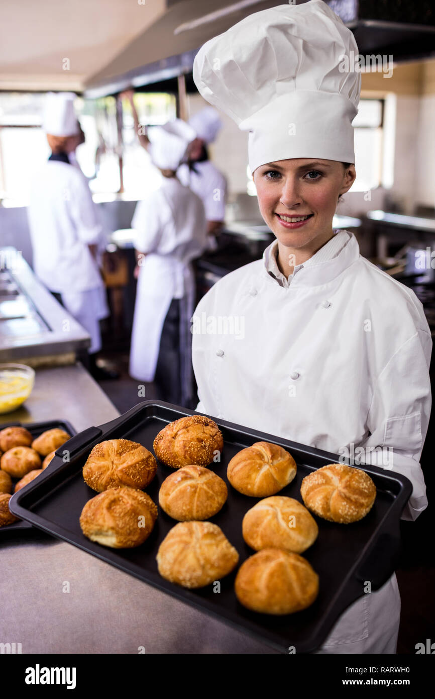 Female chefs holding baking tray of kaiser rolls in kitchen Stock Photo Alamy