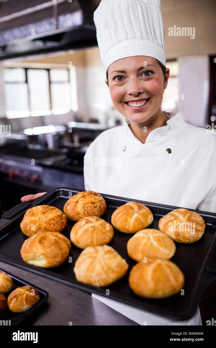 Female chefs holding baking tray of kaiser rolls in kitchen Stock Photo Alamy