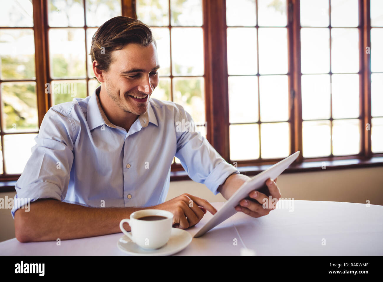 Man using digital tablet while having coffee in restaurant Stock Photo