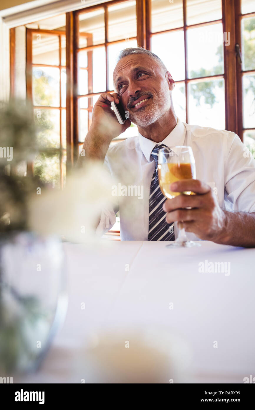 Businessman talking on mobile phone while having white wine Stock Photo