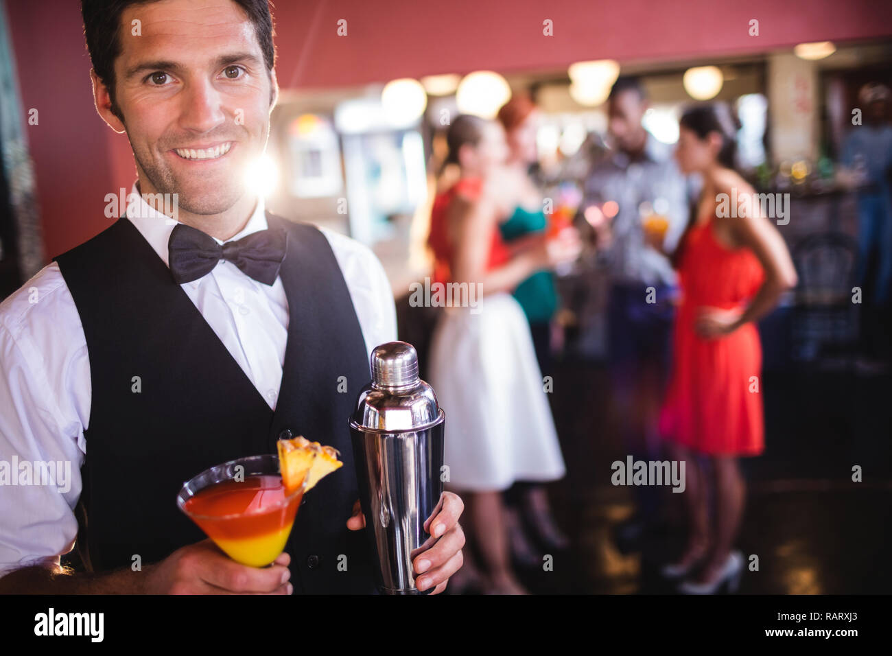 Bartender standing with cocktail glass and cocktail shaker in nightclub Stock Photo