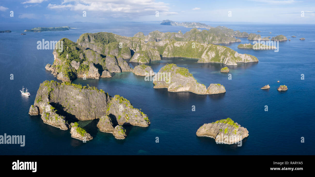 Remote limestone islands rise from the stunning seascape in Raja Ampat, Indonesia. This diverse region is known as the heart of the Coral Triangle. Stock Photo