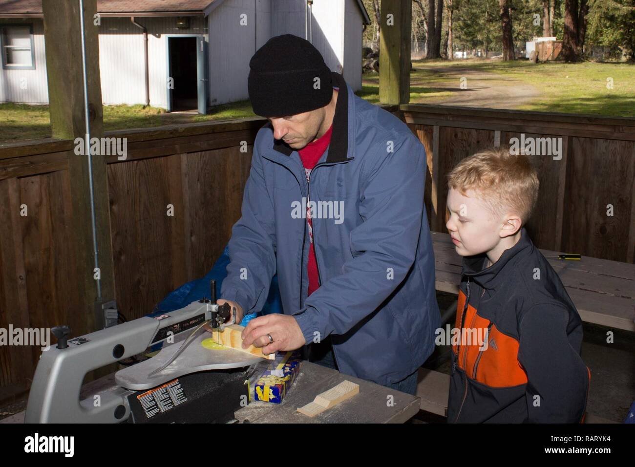 Joseph Ingle, a Scouting parent, helps Jake Johnson, a Wolf Cub Scout, cut his Pinewood Derby car at the first of two Derby Garage’s hosted by Pack 462, Feb. 11, 2016. The leaders of Pack 462 have donated their time, tools and equipment allowing these boys and their families the opportunity to use these tools that they otherwise would not. Stock Photo