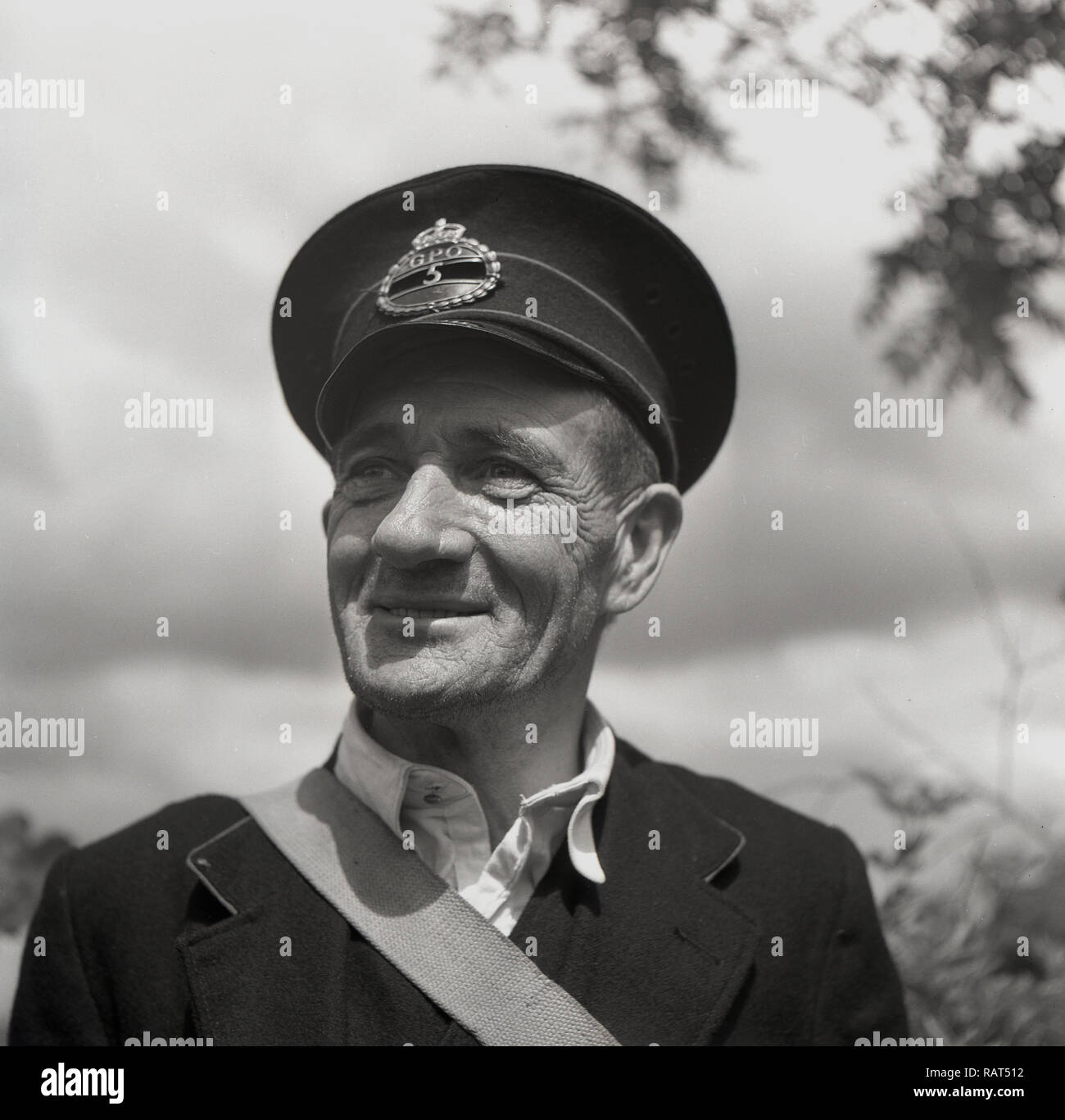 1950s, historical, portrait of a GPO postman in uniform and cap, with Kings Crown brass badge. Established in England in 1660, the General Post Office combined the functions of the state postal system and telecommunications until it was abolished in 1969 and its assets transferred to The Post Officec. Stock Photo