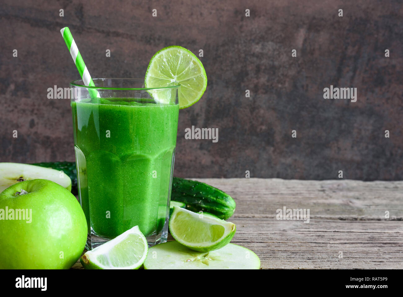 green healthy smoothie in a glass with spinach, apple, cucumber and lime with a straw. detox drink. close up Stock Photo