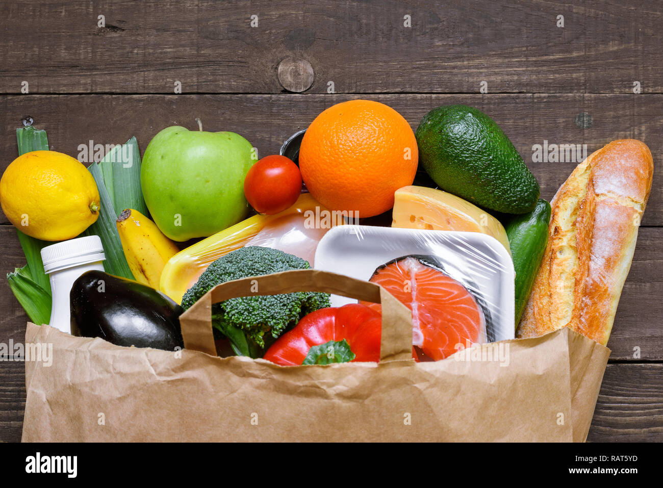 Different food in paper bag on rustic wooden background. close up. Grocery shopping concept. top view Stock Photo