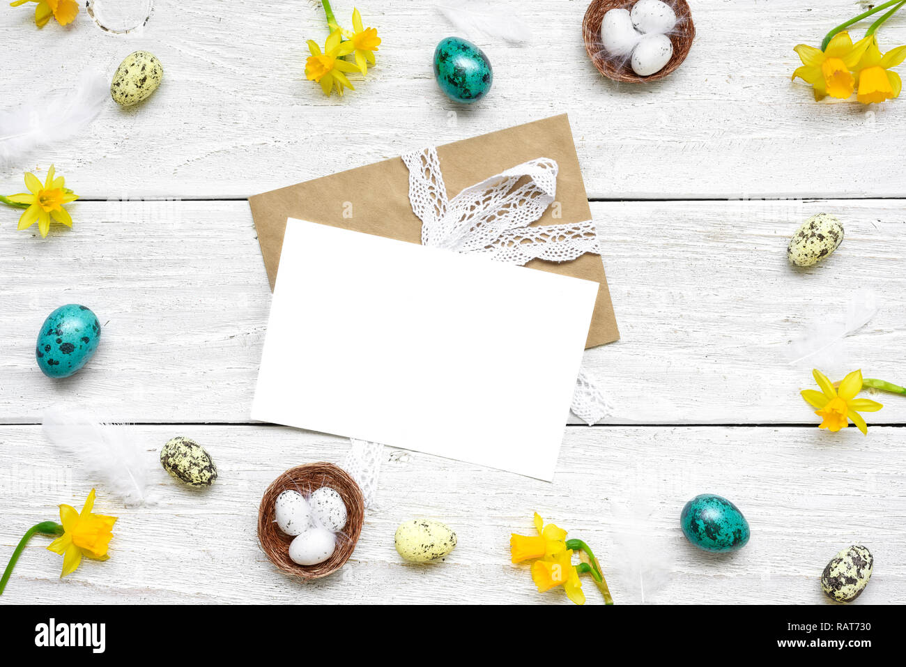 easter greeting card in frame made of quail eggs, spring flowers and feathers on white wooden background. easter composition. top view with copy space Stock Photo