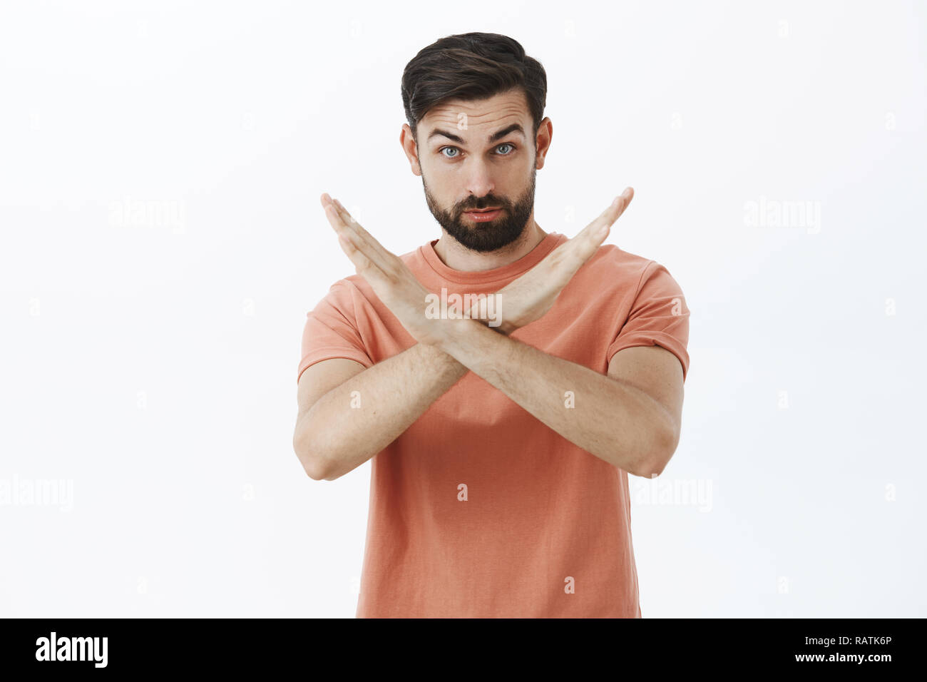 You must stop. Portrait of serious and confident bearded male friend showing cross with hands making not and prohibition gesture demanding quit, forbid some action over gray background Stock Photo