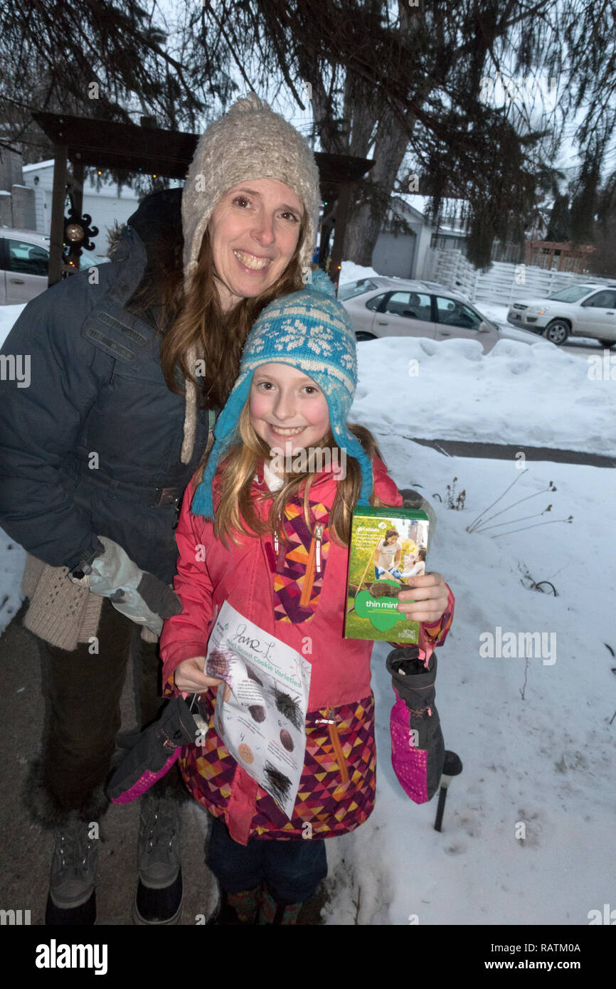 Mother and daughter selling Girl Scouts cookies door to door in winter weather. St Paul Minnesota MN USA Stock Photo