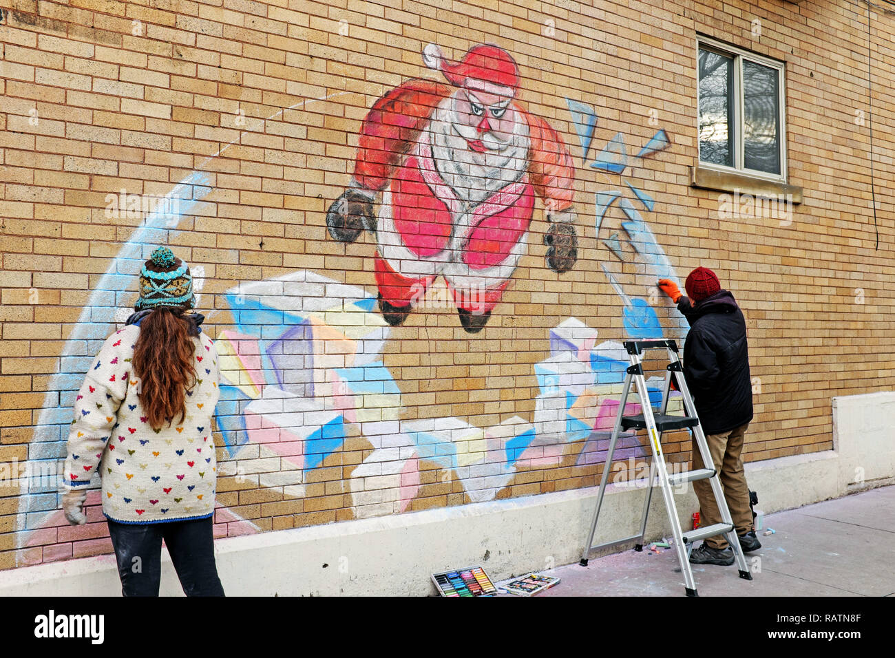 Two people chalk a holiday scene on the side of a business on West 65th during the 2019 Gordon Square Winterfest in Cleveland, Ohio, USA. Stock Photo