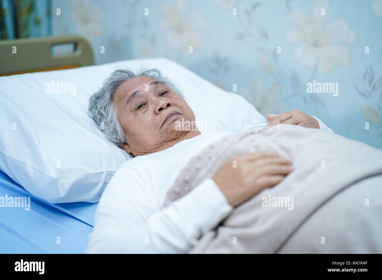 Asian senior or elderly old lady woman patient smile bright face with strong health while lying on bed in nursing hospital ward : healthy medicine. Stock Photo